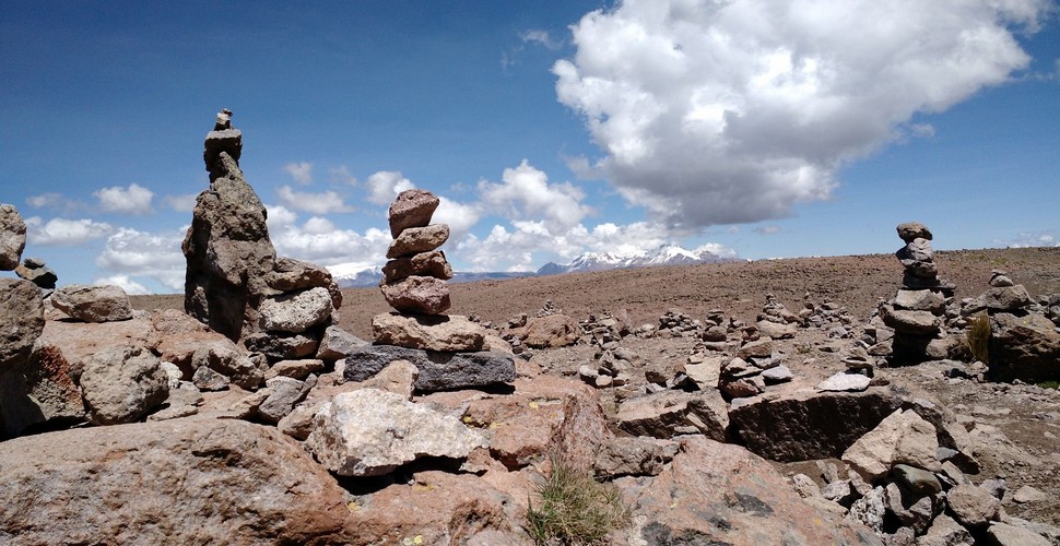 During pilgrimages in The Andes, participants may build apachetas along the route as they journey to sacred sites. Mountains, lakes, or shrines, seen on your Peru vacation packages, may be surrounded by apachetas.